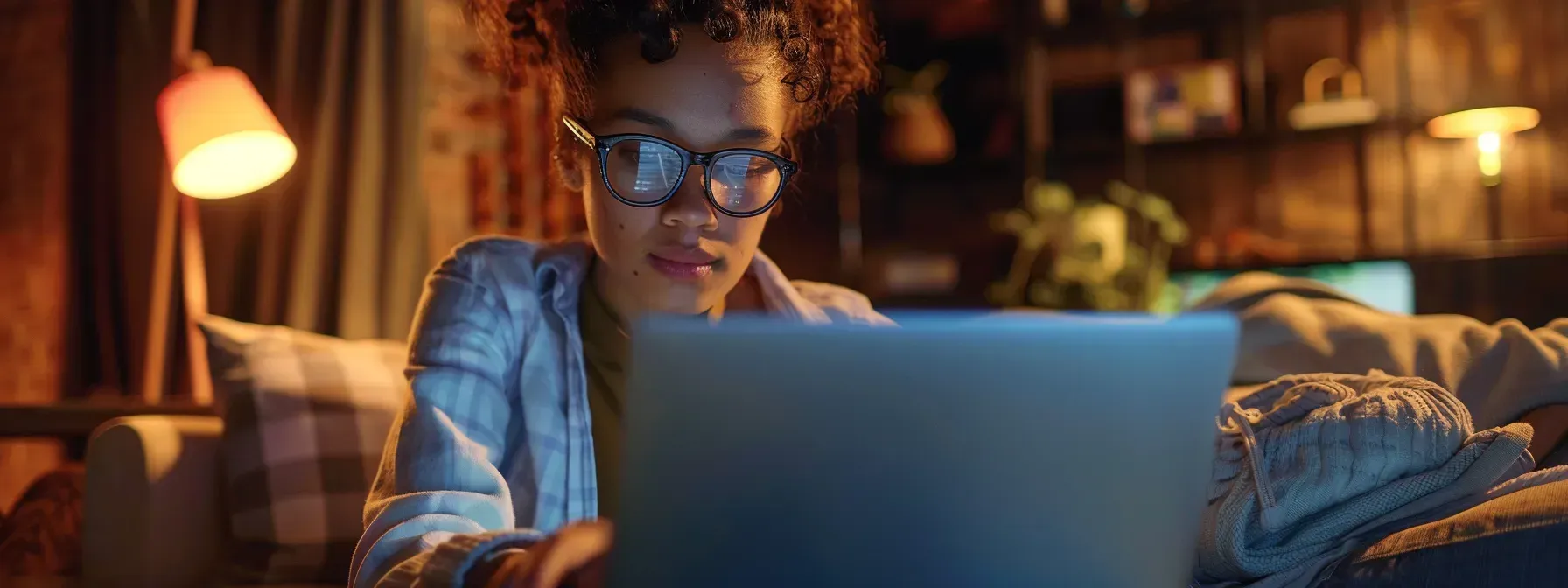 A woman is sitting on a couch using a laptop computer.