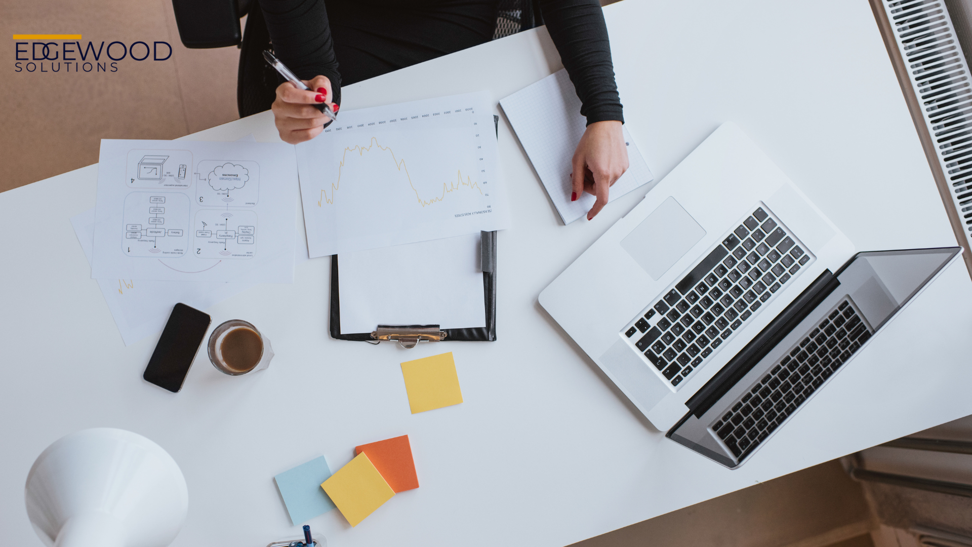 A fractional cmo is sitting at a desk with a laptop and a pen.