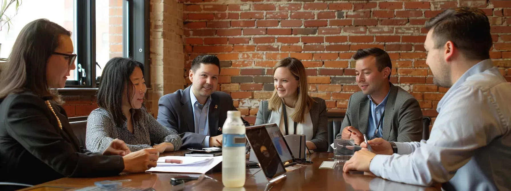 A group of people are sitting around a table having a meeting.