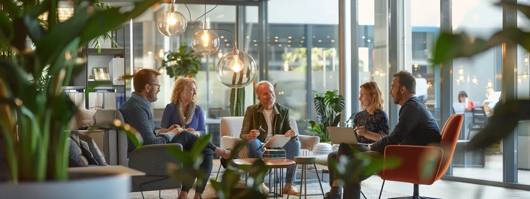 A group of people are sitting around a table in an office having a meeting.