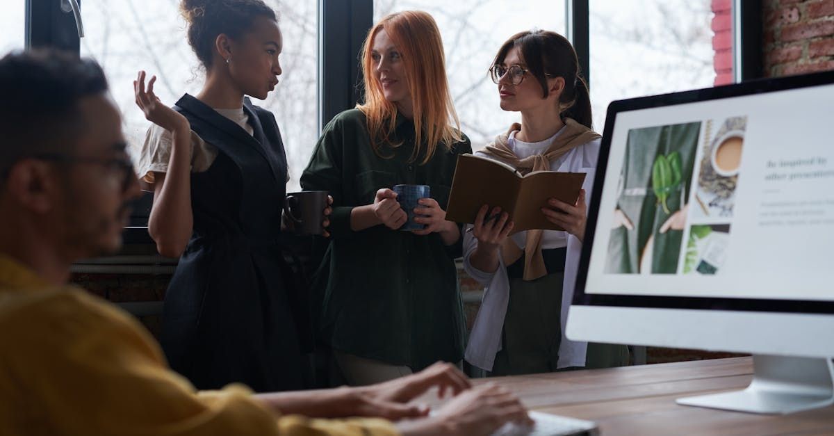 A group of people are standing around a computer monitor.