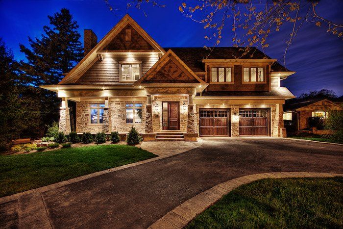 A large house is lit up at night with a driveway in front of it.