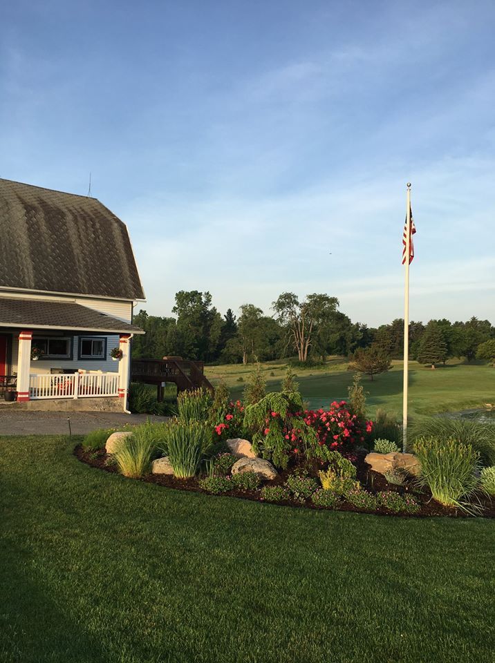 A white barn is sitting in the middle of a lush green field.