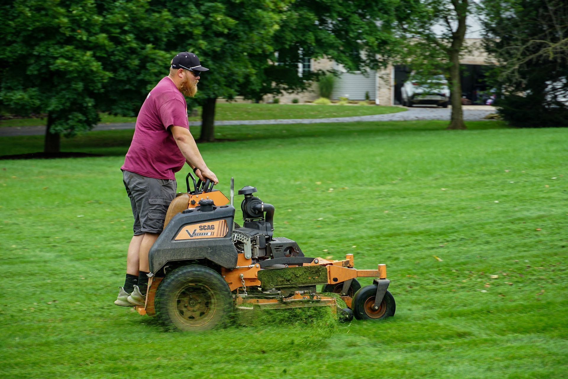 A man is riding a lawn mower on a lush green lawn.