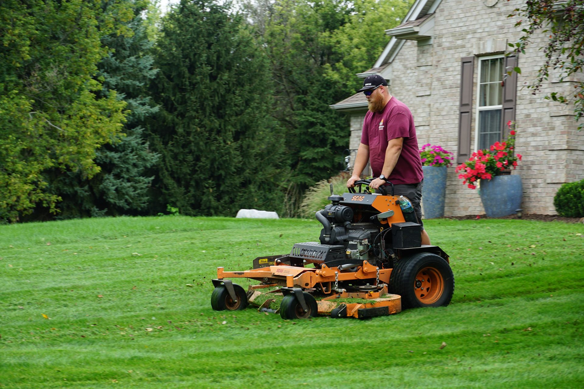 A man is riding a lawn mower on a lush green lawn.