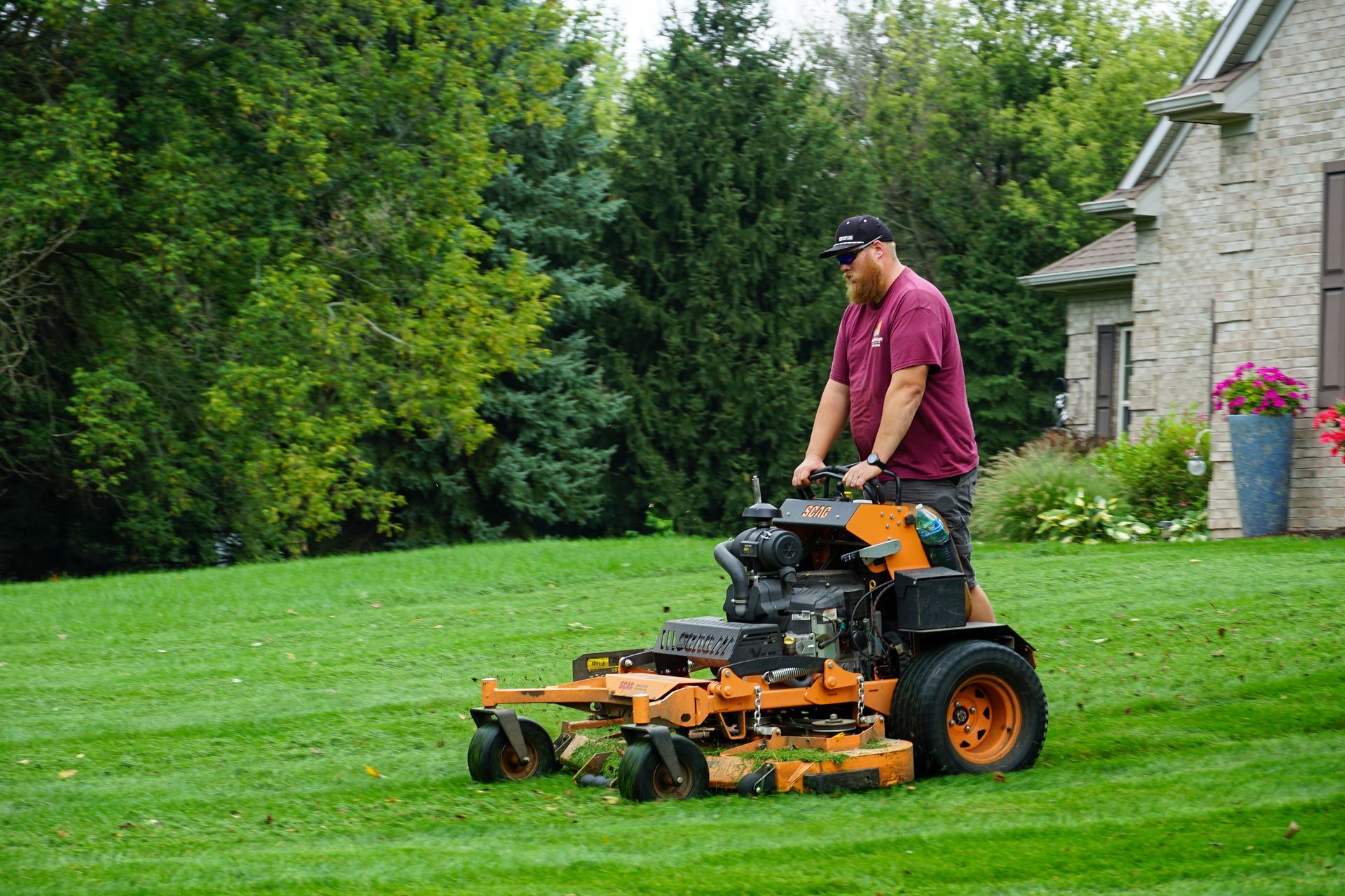 A man is riding a lawn mower on a lush green lawn.