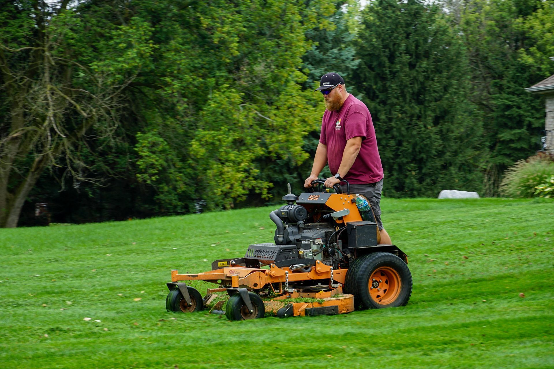 A man is riding a lawn mower on a lush green lawn.