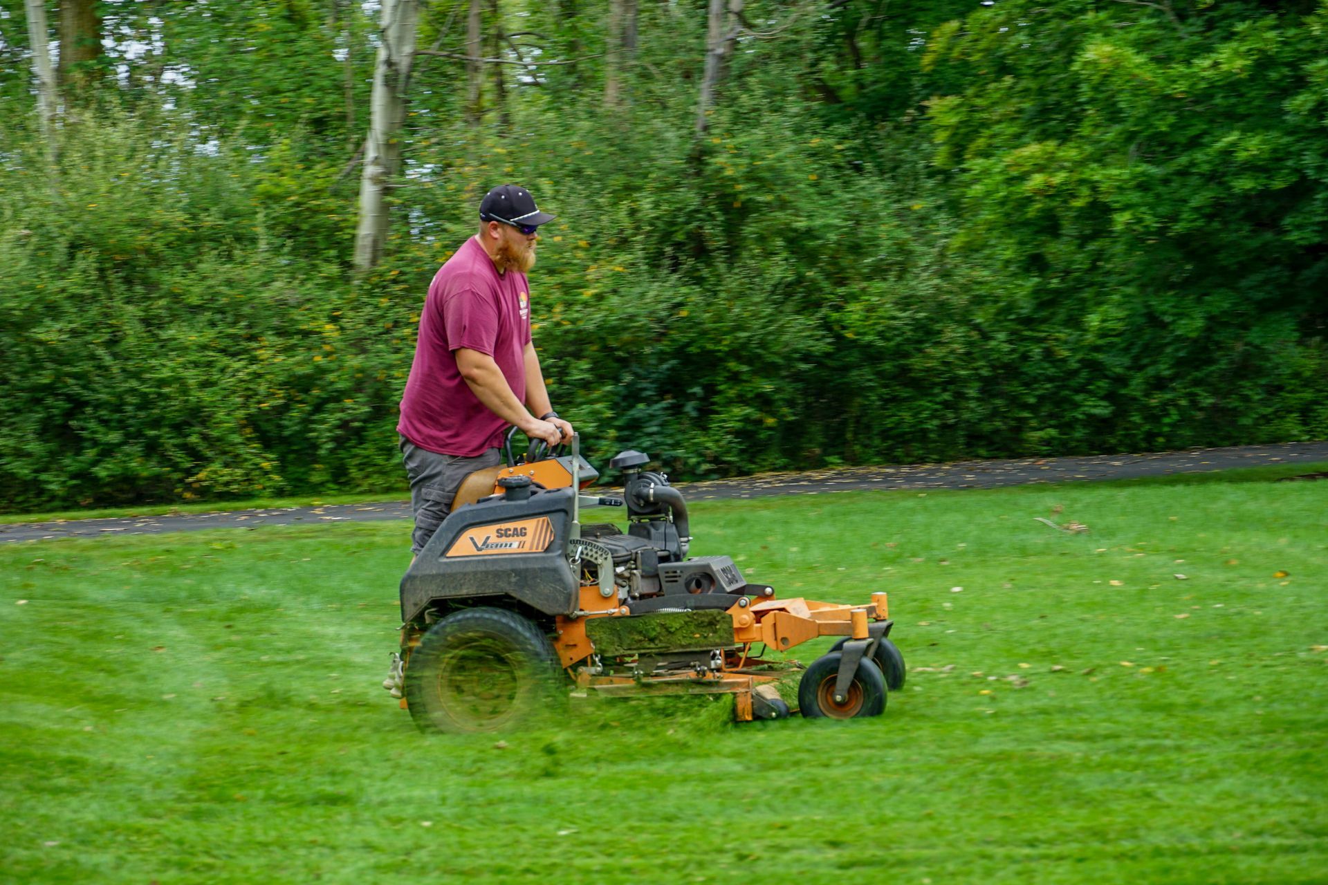 A man is riding a lawn mower on a lush green lawn.