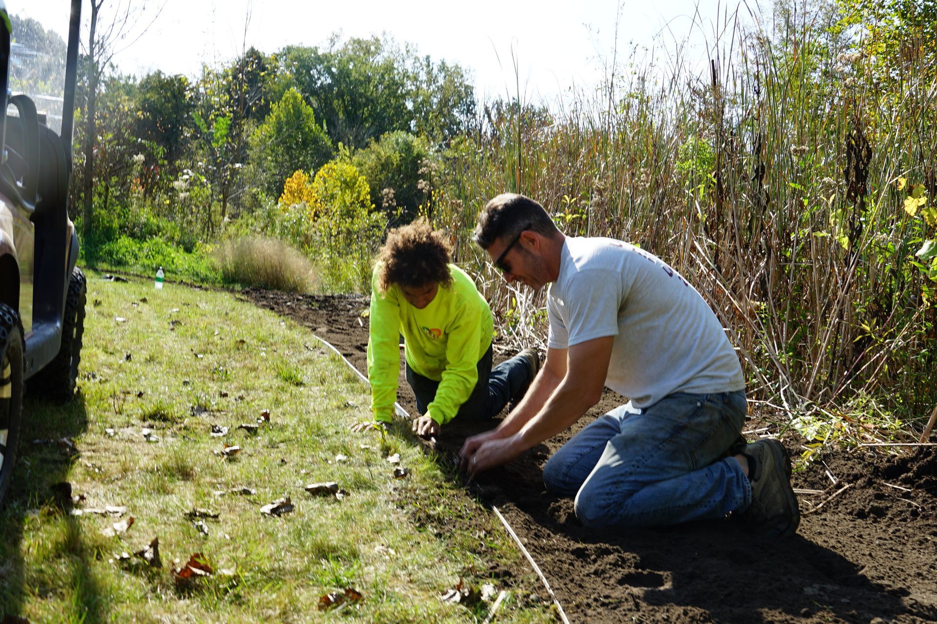 A man and a woman are kneeling down in the dirt.