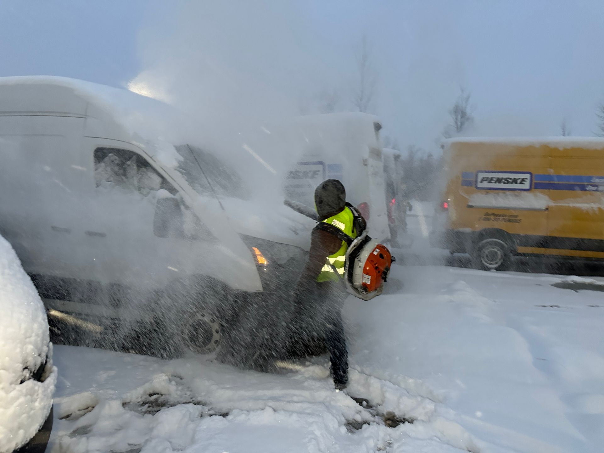 A man is using a snow blower to clear snow from a parking lot.