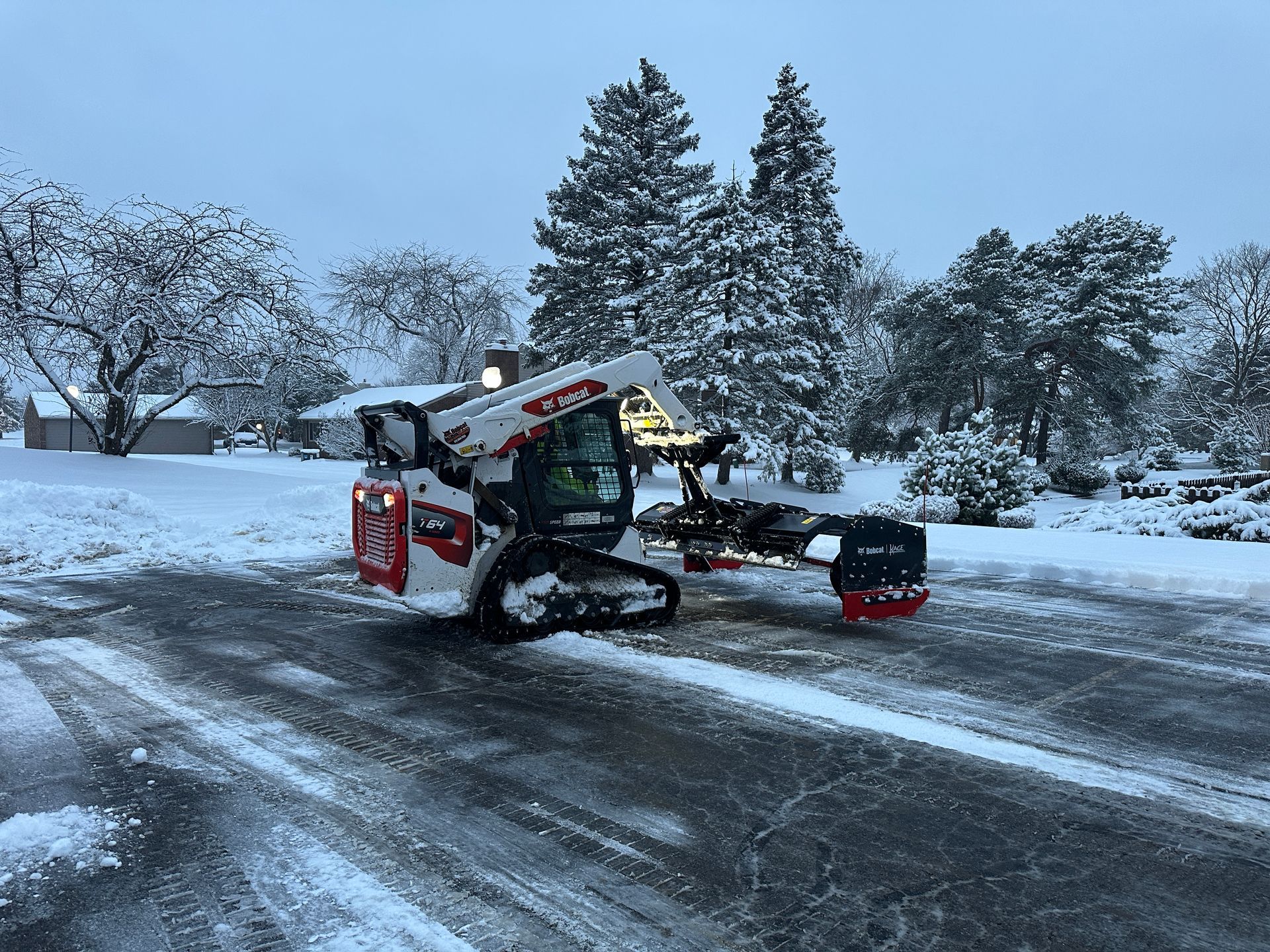 A snow plow is driving down a snow covered road.