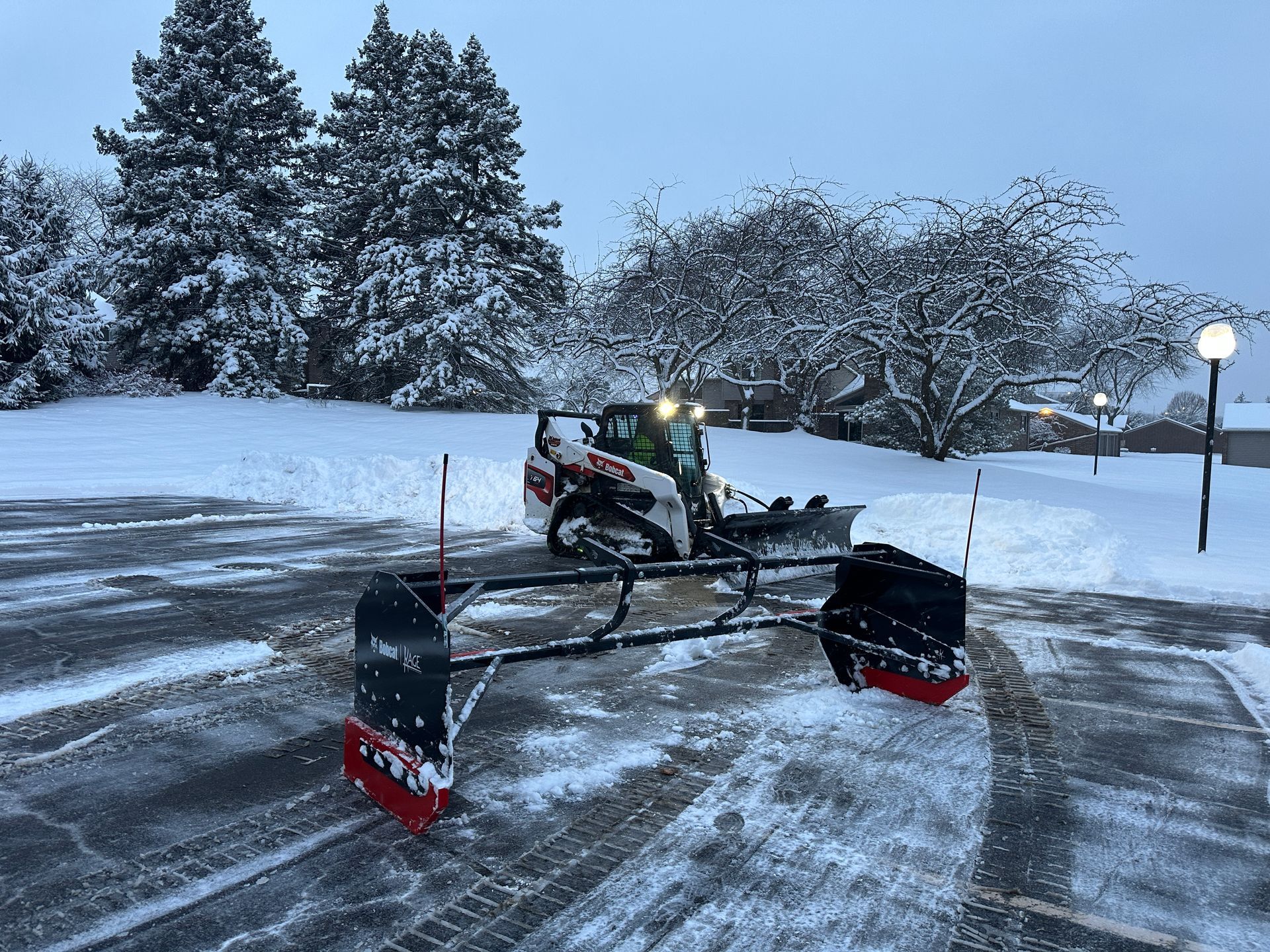 A snow plow is plowing snow in a parking lot.