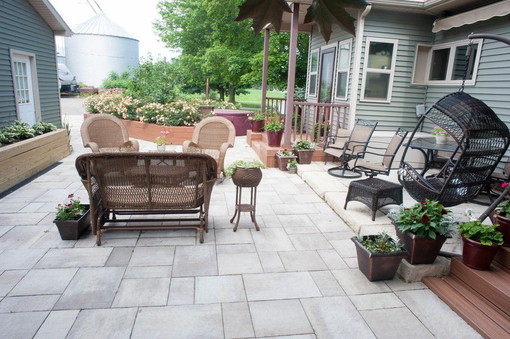 A patio with wicker furniture and potted plants in front of a house