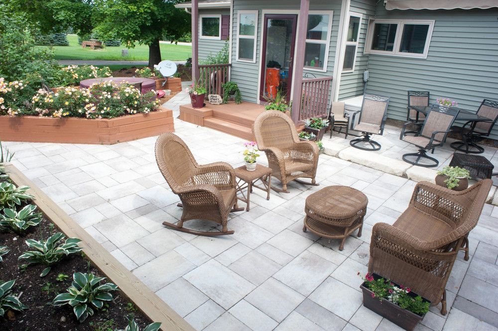 A patio with rocking chairs and a table in front of a house