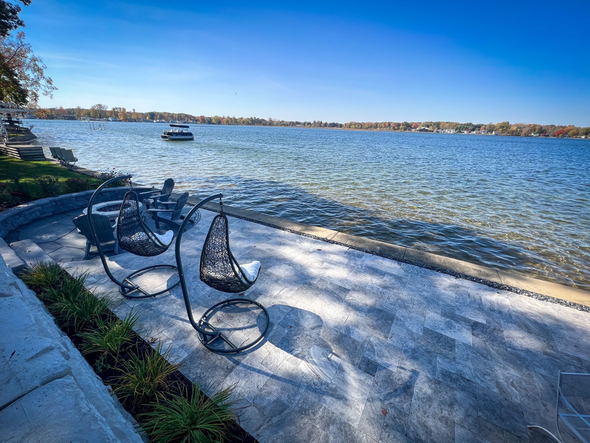 A couple of chairs sitting on a patio next to a body of water.