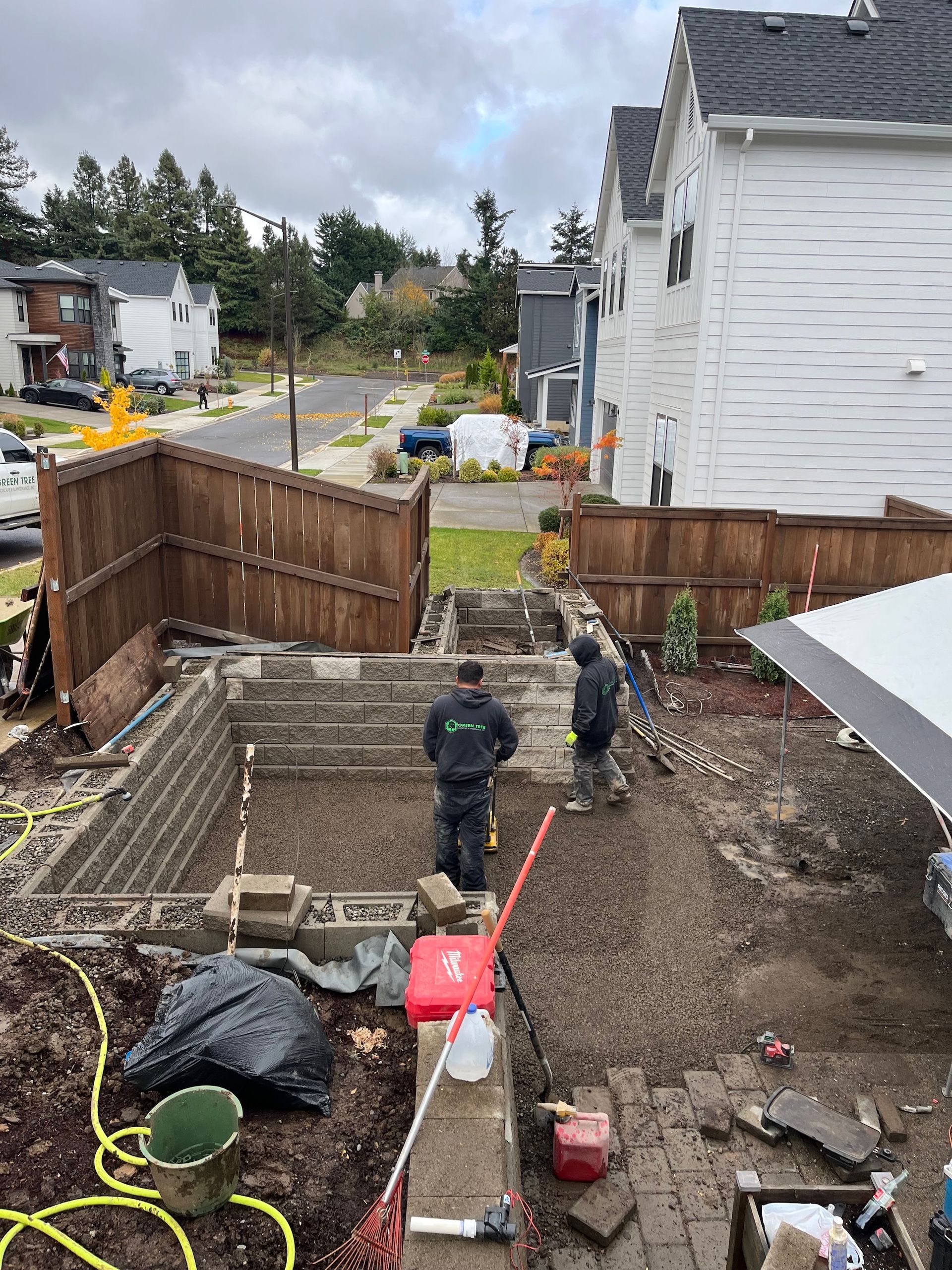 A group of people are working on a hardscaping construction in a backyard.