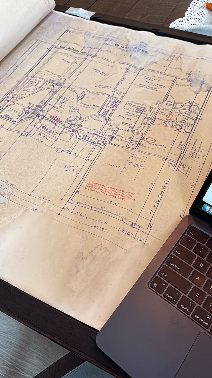 Large sheet covered in handwritten notes and sketches beside an open laptop on a desk