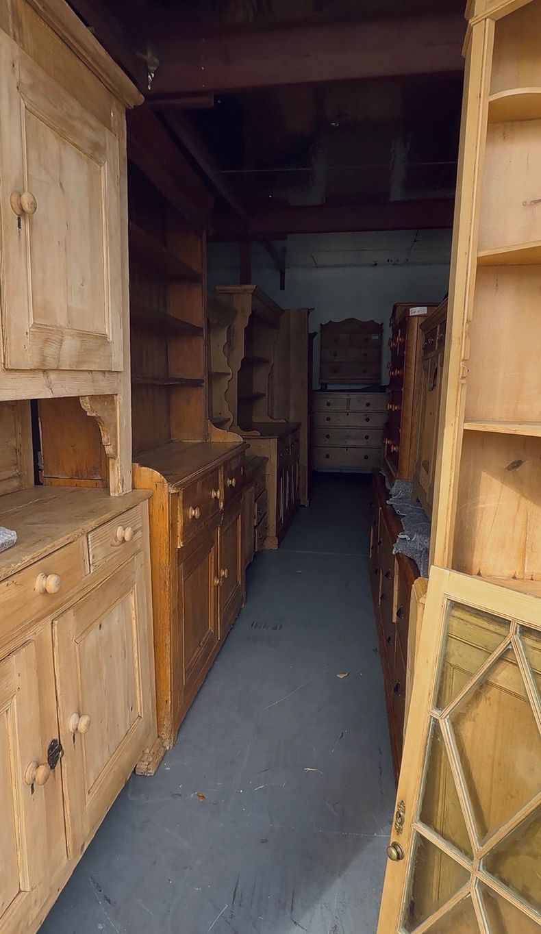 Narrow storage aisle lined with wooden crates and shelves in a dim warehouse