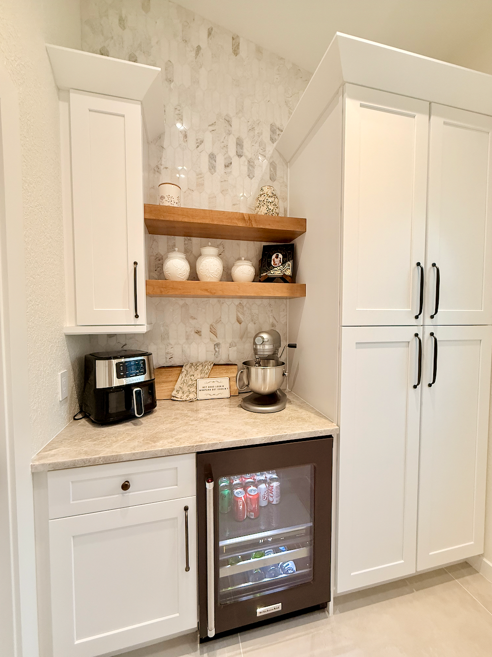 Built-in coffee bar with white cabinets, marble countertop, espresso machine, and wine cooler.