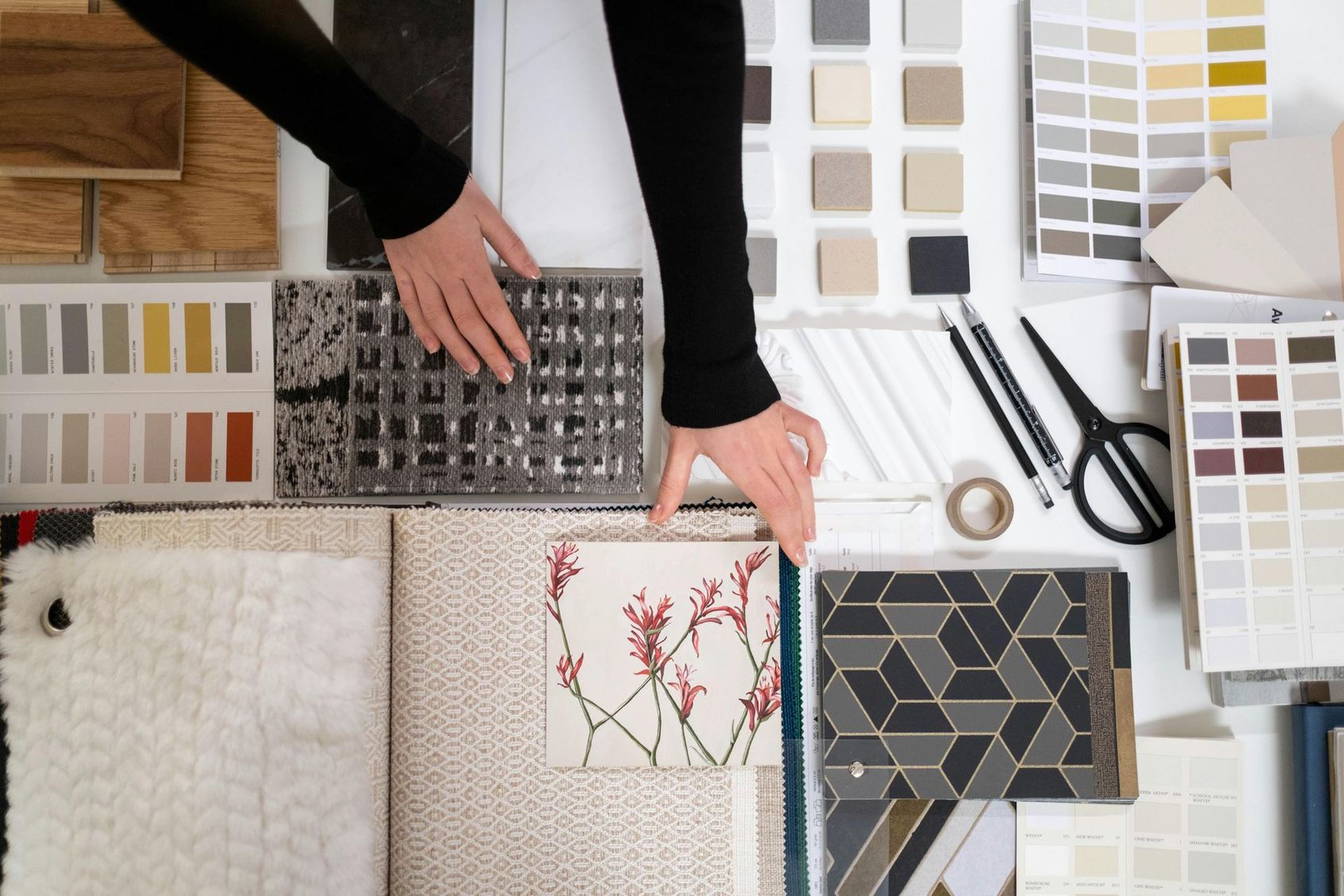 Hand selecting patterned fabric swatches and color samples on a design worktable