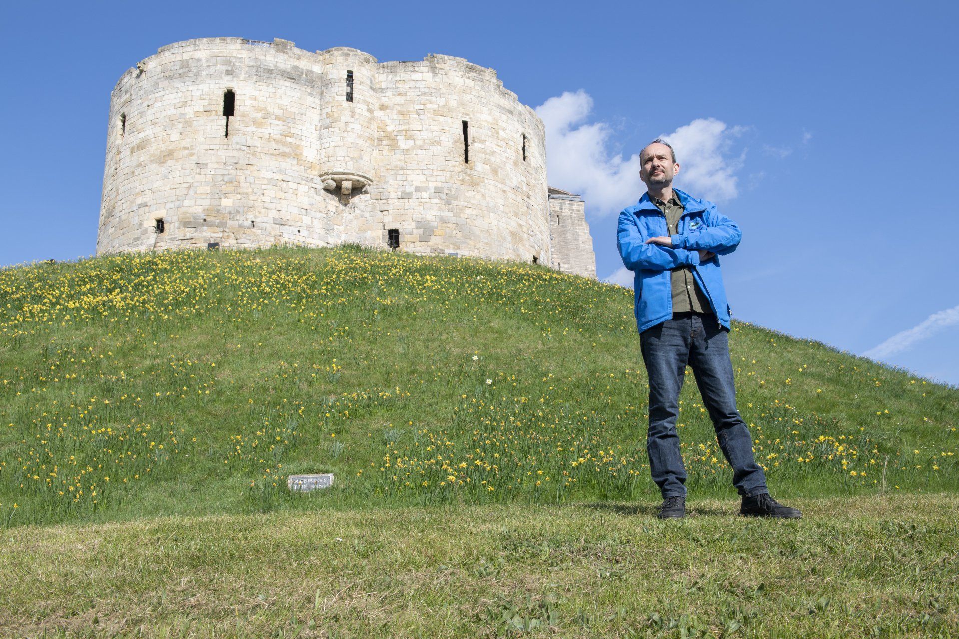 J&M City walks Tour guide stands outside Cliffords Tower in York guiding tourist on history