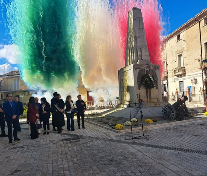 La gente osserva un monumento mentre nell'aria si alza un fumo colorato che rappresenta la bandiera italiana.
