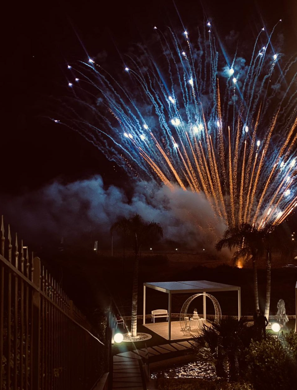 Spettacolo pirotecnico notturno su un'area giardino con gazebo con posti a sedere.