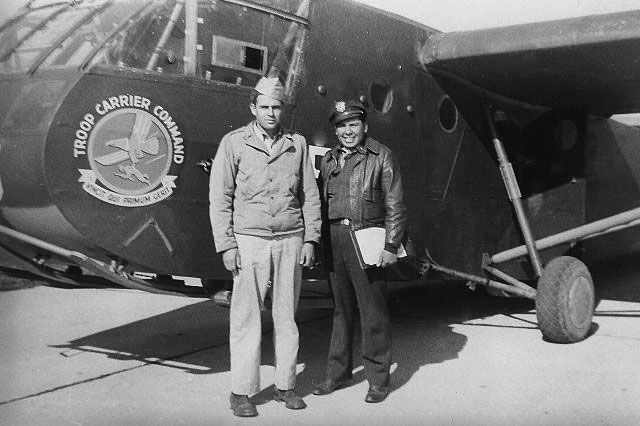 Two men standing in front of a plane that says trans carrier company