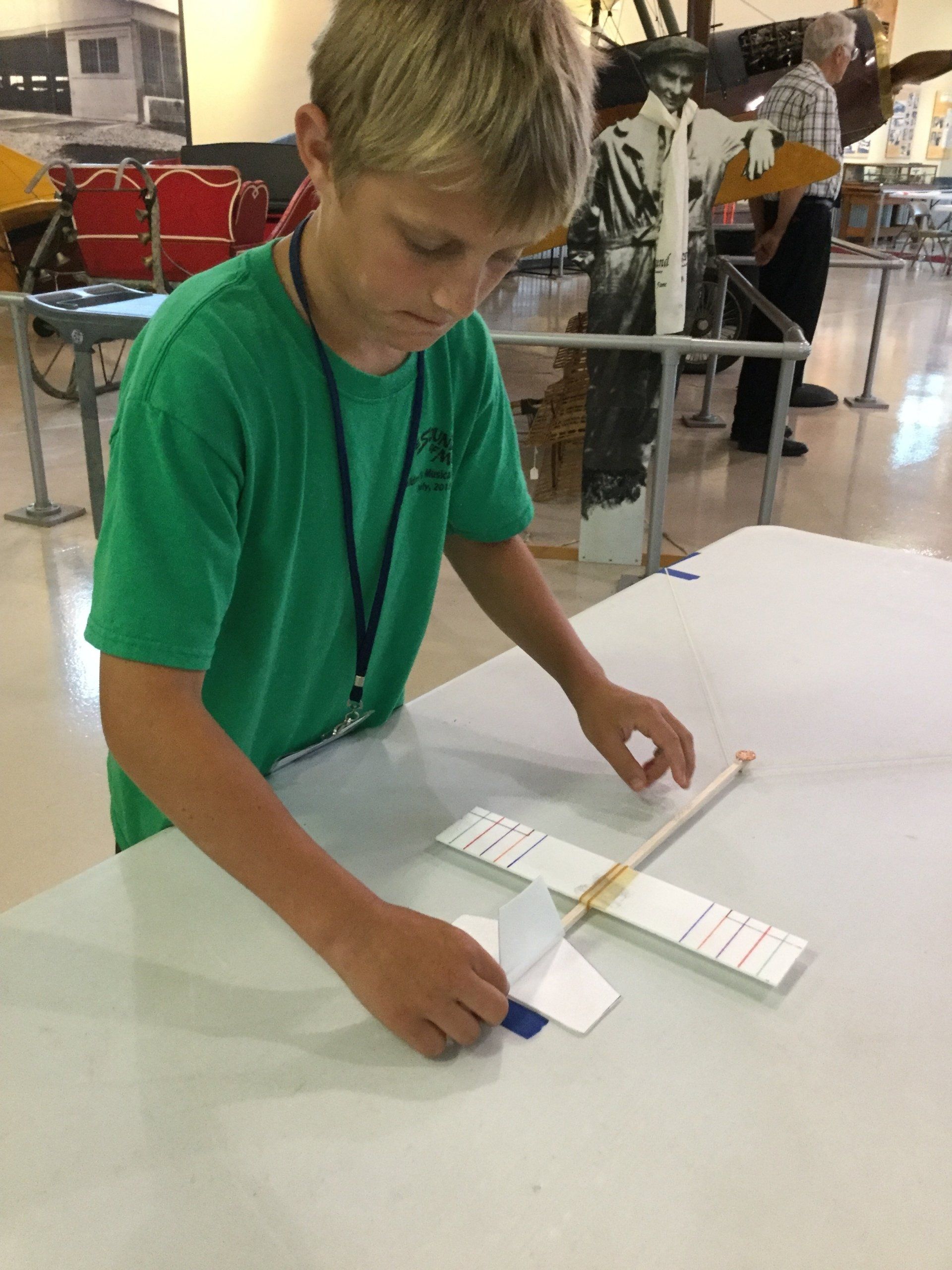 A young boy in a green shirt is playing with a paper airplane