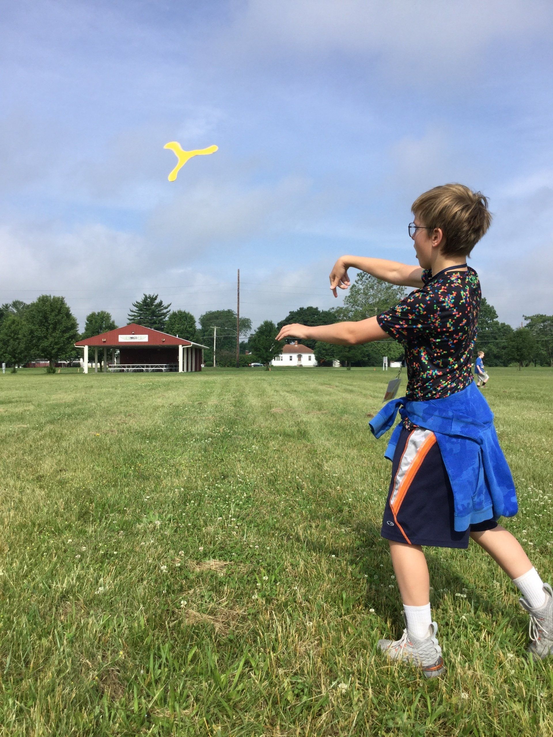 A young boy is playing with a boomerang in a grassy field.