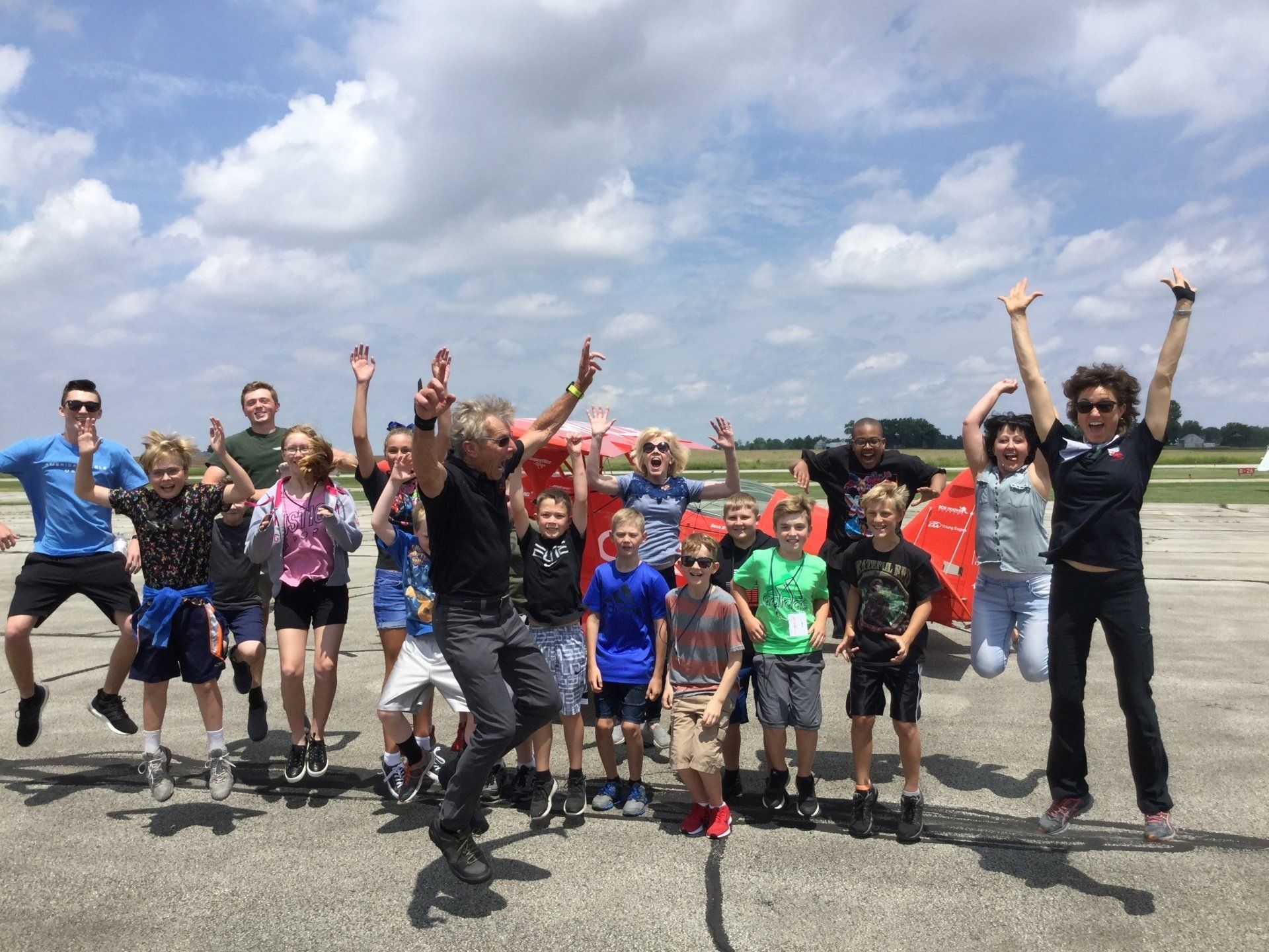 A group of people are jumping in the air in front of a plane.