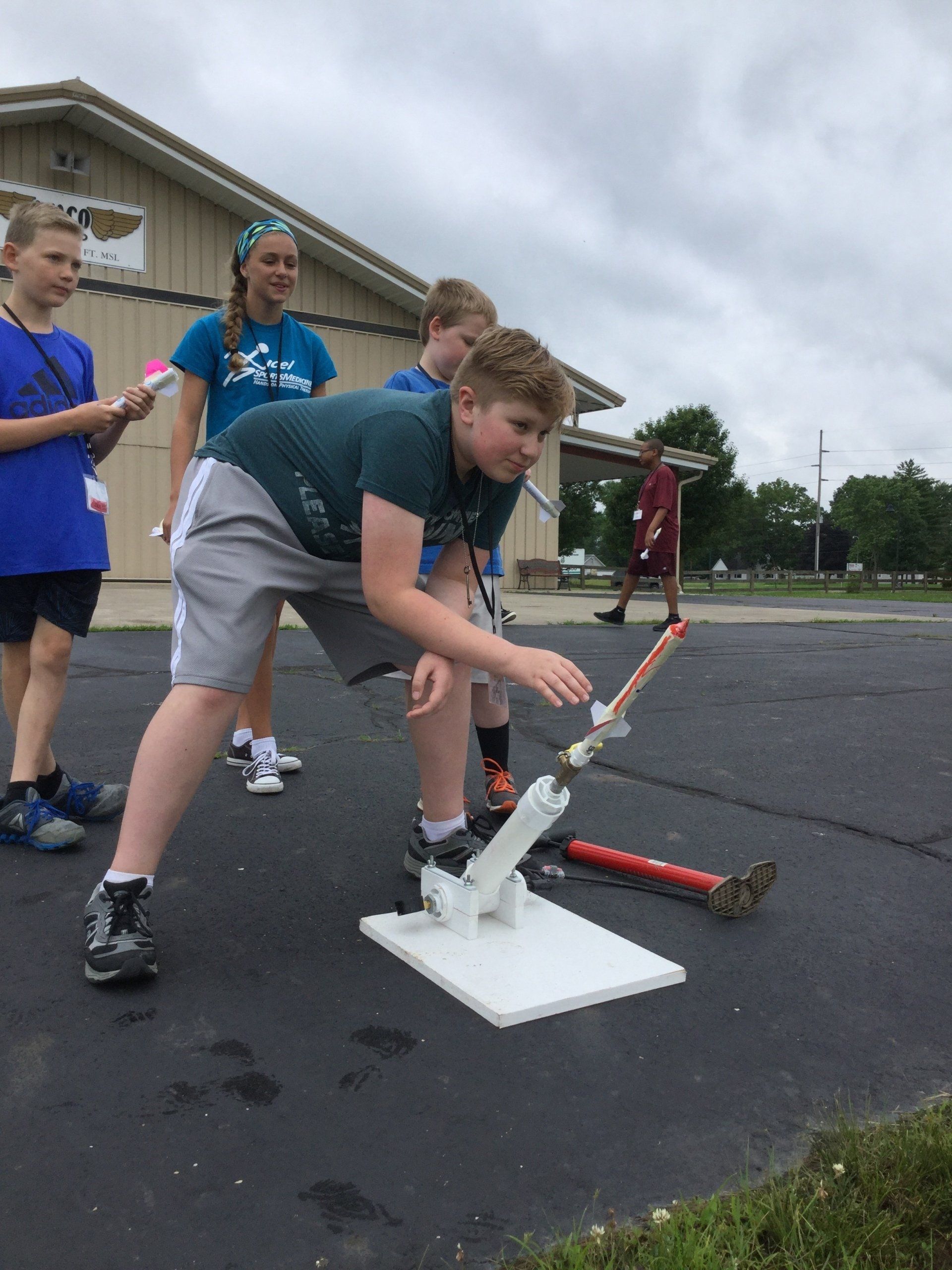 A group of children are playing with a rocket in a parking lot.