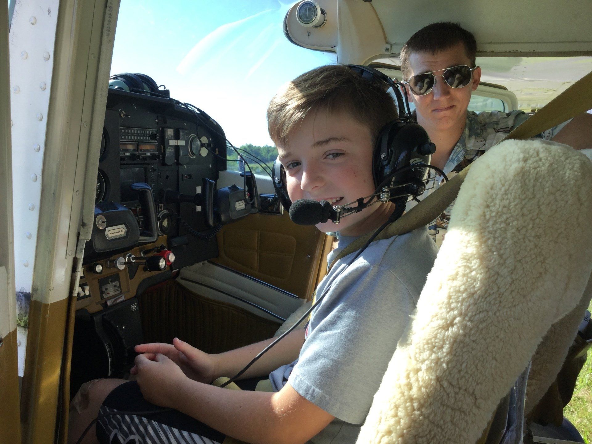A boy wearing headphones is sitting in the cockpit of an airplane