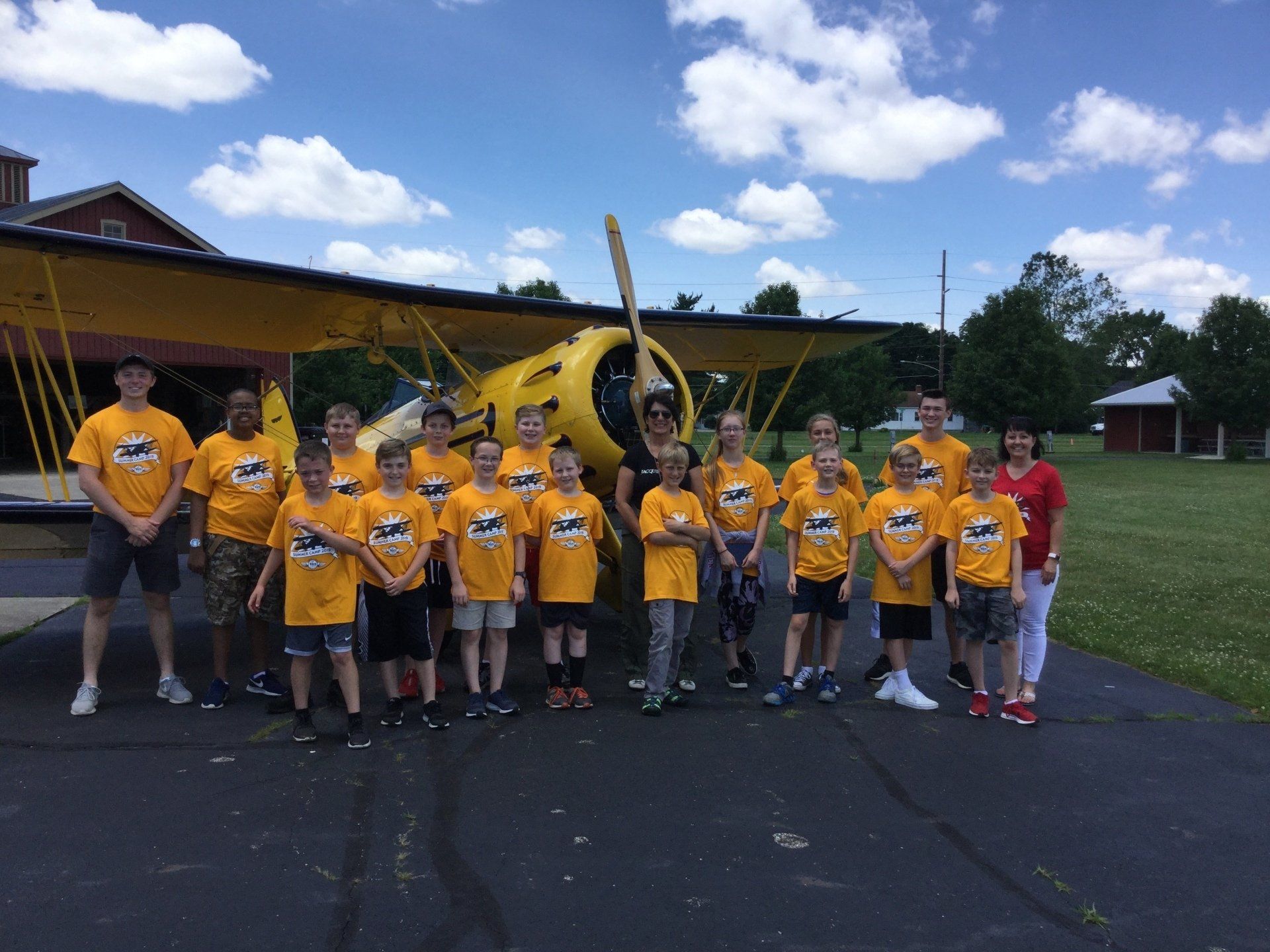 A group of children are posing for a picture in front of a yellow airplane.