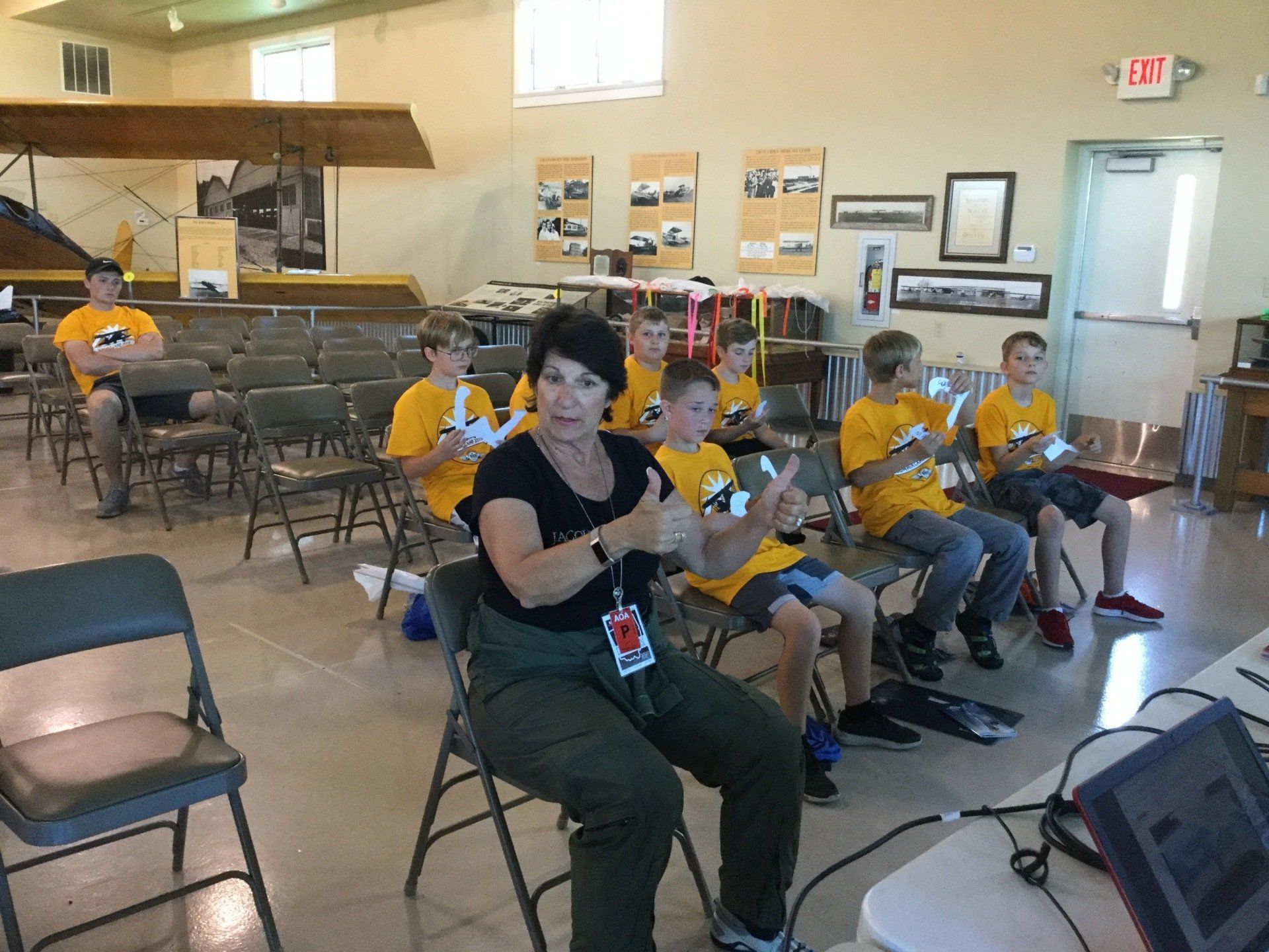 A woman is sitting in front of a group of children playing video games.