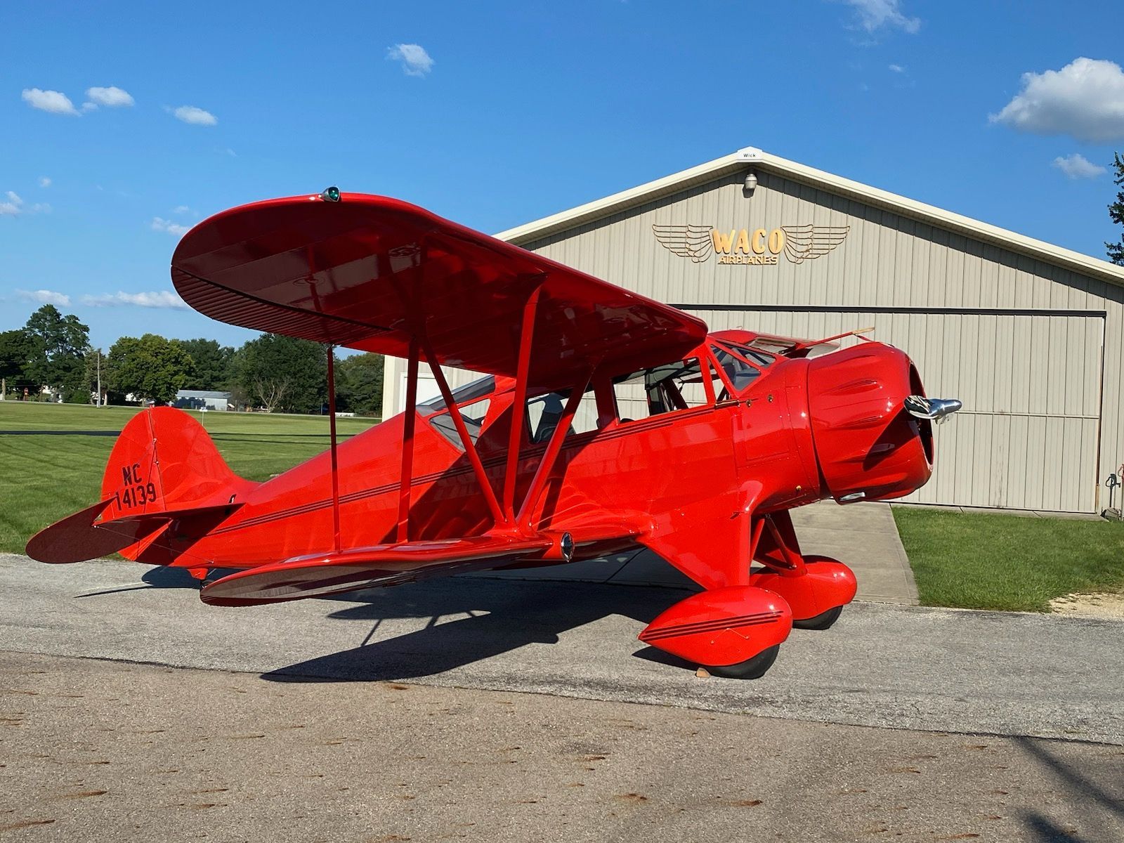 A red airplane is parked in front of a building