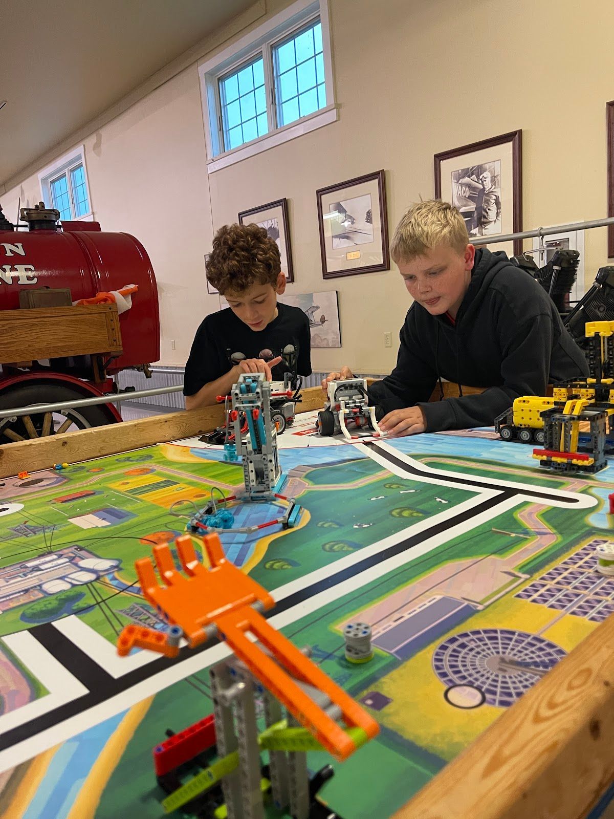Two young boys are playing with lego robots on a table.