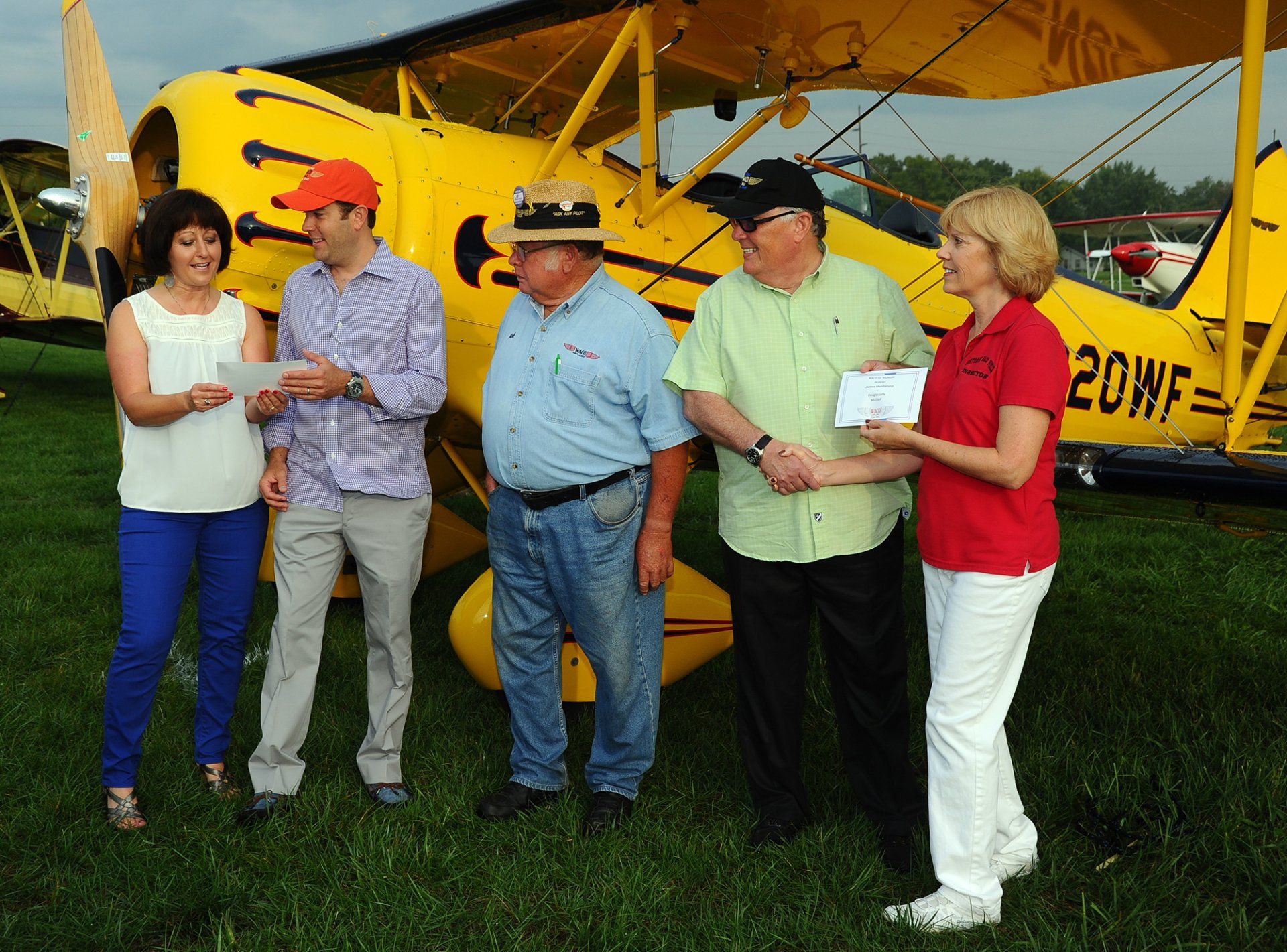 A group of people standing in front of a yellow plane that says 20wf
