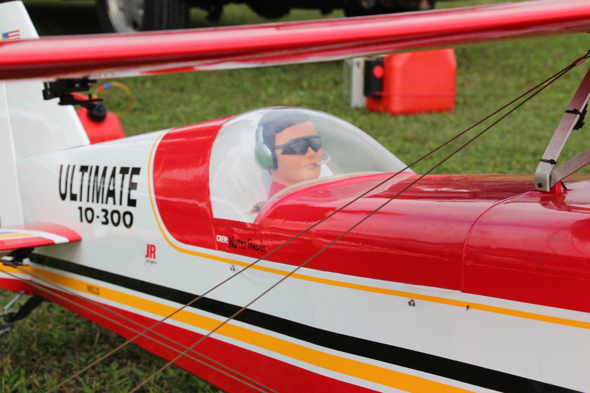 A red and white model airplane with a man in the cockpit.