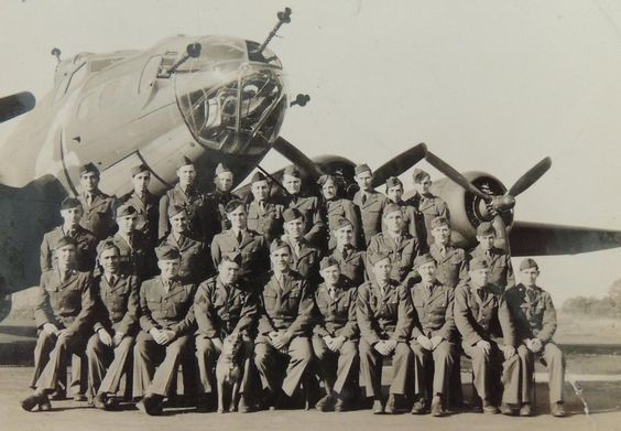 A group of men are posing for a picture in front of an airplane