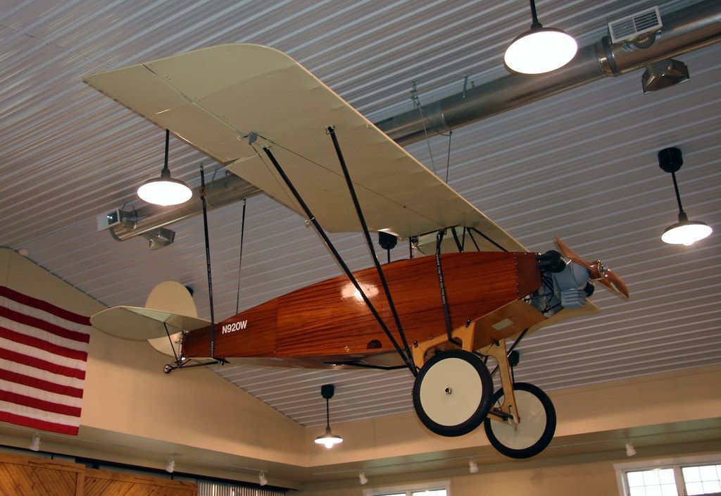 A small plane is hanging from the ceiling in a room