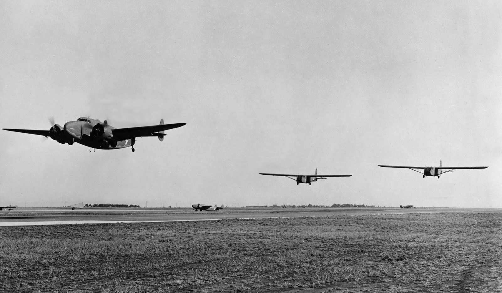Three planes are taking off from a runway in a black and white photo