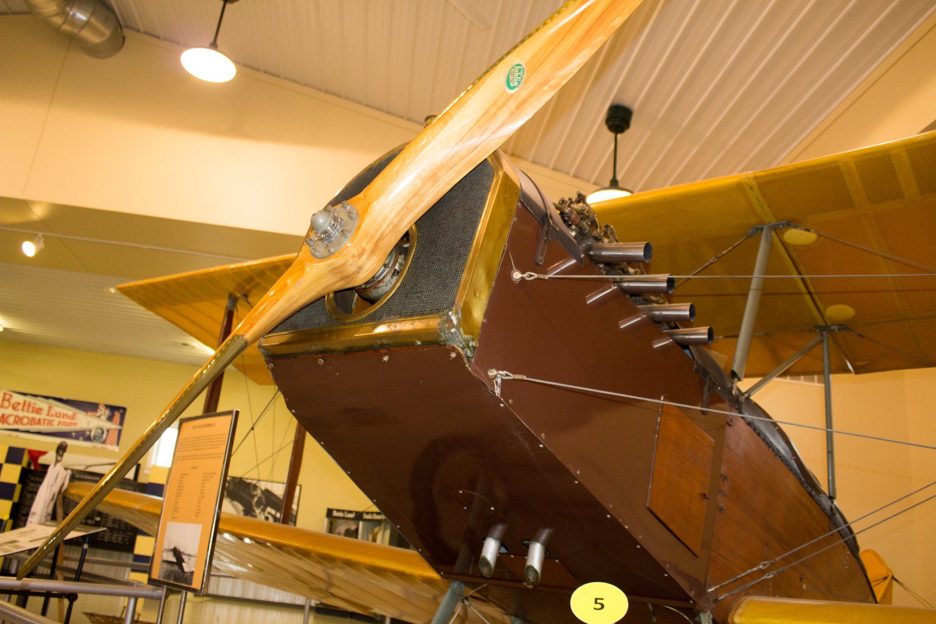 A brown and yellow airplane with a propeller hanging from the ceiling