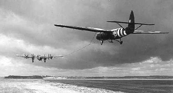 A black and white photo of a plane being towed by another plane.