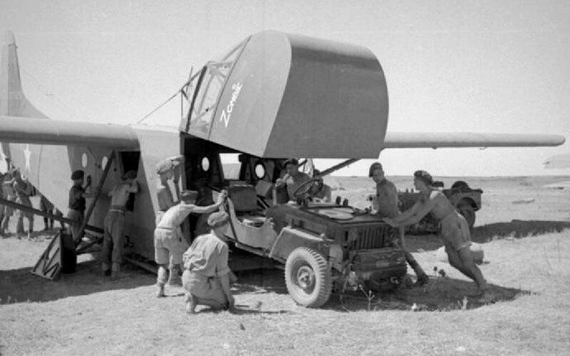 A black and white photo of a group of men working on a plane