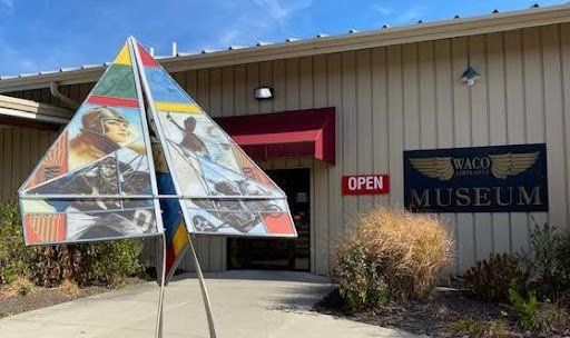A triangle shaped sculpture is in front of a museum.