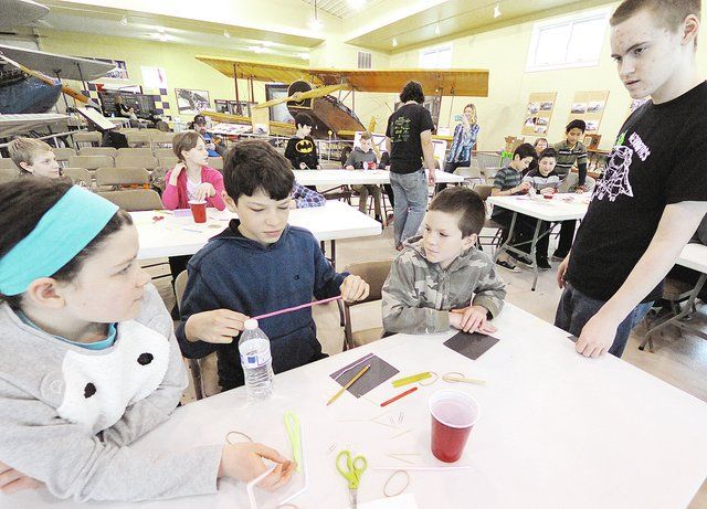 A group of children are sitting around a table making crafts