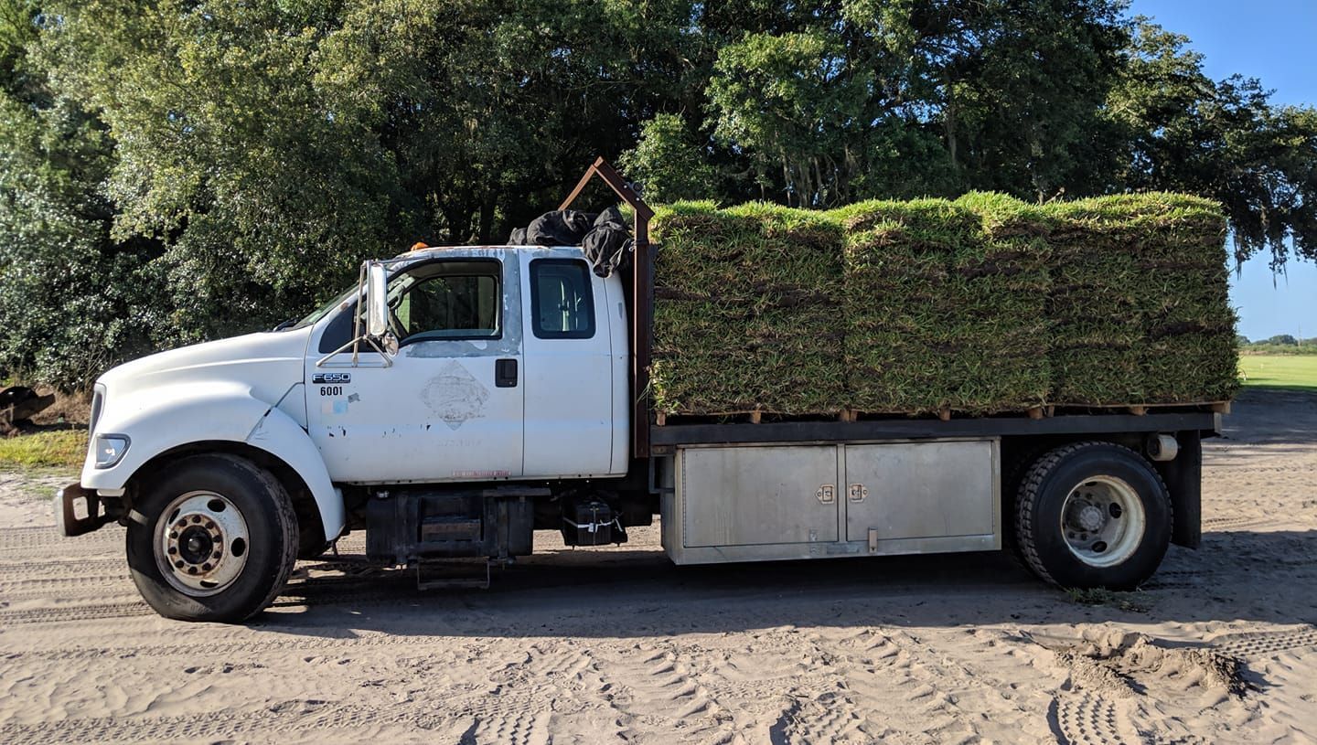 A white truck is loaded with bales of grass