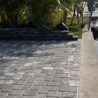 A brick driveway is being built next to a palm tree