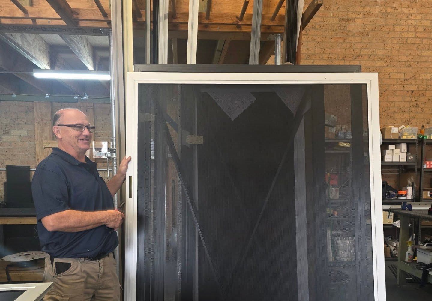 A Man is Standing Next to a Screen Door — Everything Screendoors & More In Wollongong, NSW